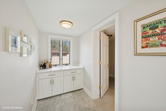bar area featuring baseboards and light tile patterned flooring