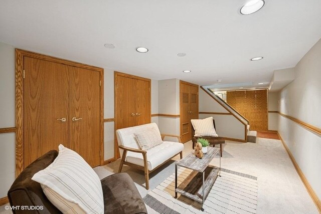 living area featuring light colored carpet, baseboards, recessed lighting, and stairs