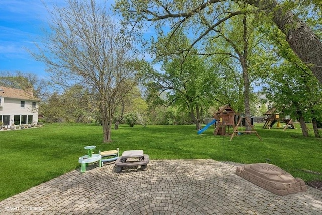 view of green lawn featuring a playground and a patio