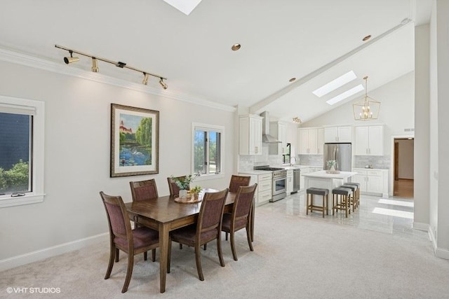dining area with a skylight, rail lighting, crown molding, a chandelier, and baseboards