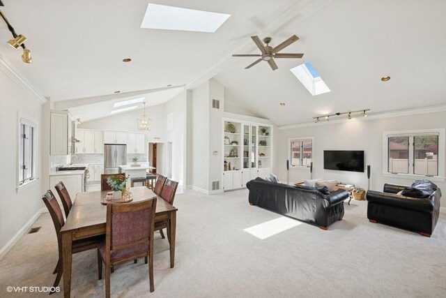 living room with a skylight, light colored carpet, baseboards, ornamental molding, and high vaulted ceiling