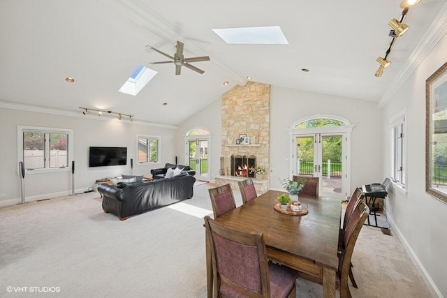 dining room with a skylight, light carpet, baseboards, track lighting, and crown molding