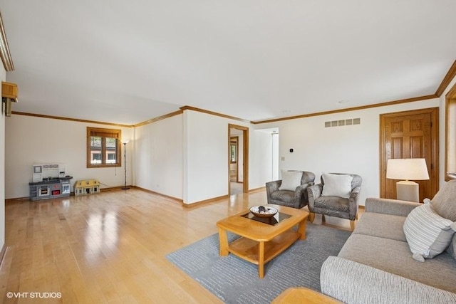 living area featuring light wood-style floors, baseboards, and crown molding