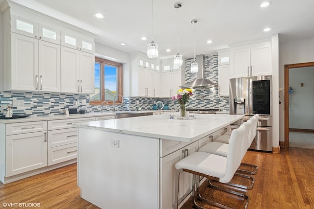 26464 N Bittersweet Trl, Mundelein, IL 60060 - kitchen featuring stainless steel refrigerator with ice dispenser, wall chimney exhaust hood, a kitchen island, white cabinets, and light wood finished floors