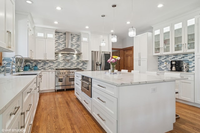 26464 N Bittersweet Trl, Mundelein, IL 60060 - kitchen with appliances with stainless steel finishes, wall chimney exhaust hood, a center island, tasteful backsplash, and white cabinetry