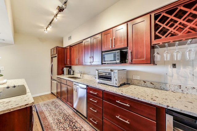 3180 N Lake Shore Dr Unit 4F, Chicago, IL 60657 - kitchen with stainless steel appliances, a sink, reddish brown cabinets, light stone countertops, and light wood-style floors