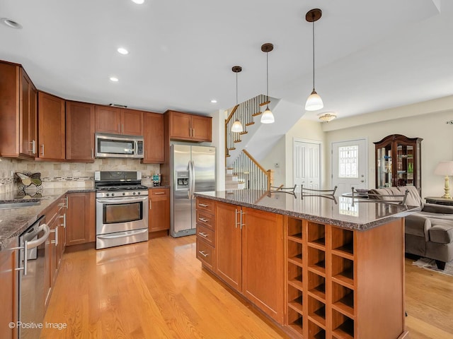 504 S Pierce Ave, Wheaton, IL 60187 - kitchen featuring stainless steel appliances, light wood-style floors, dark stone counters, open floor plan, and decorative backsplash