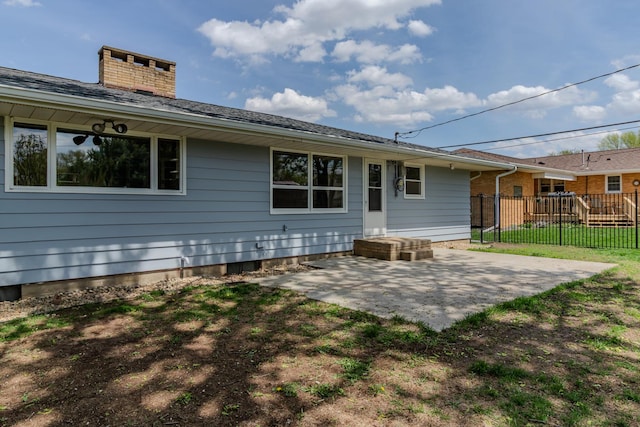 rear view of property featuring fence, a patio, and a chimney