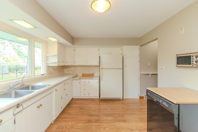 kitchen with freestanding refrigerator, dishwashing machine, a sink, light wood-style floors, and white cabinets
