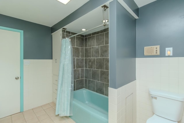 full bath with tile walls, shower / bath combination with curtain, tile patterned flooring, wainscoting, and toilet