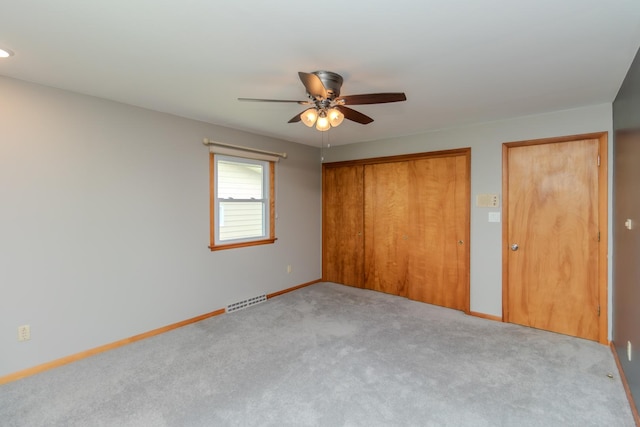 unfurnished bedroom with carpet floors, a closet, baseboards, and a ceiling fan