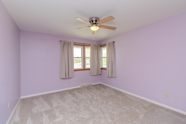 carpeted spare room with ceiling fan and baseboards
