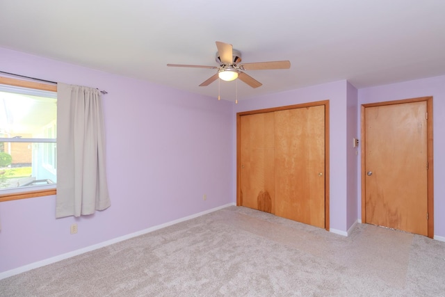 unfurnished bedroom featuring carpet floors, a closet, baseboards, and a ceiling fan