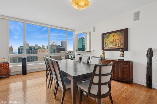 dining space featuring a city view, a wealth of natural light, light wood-type flooring, and visible vents
