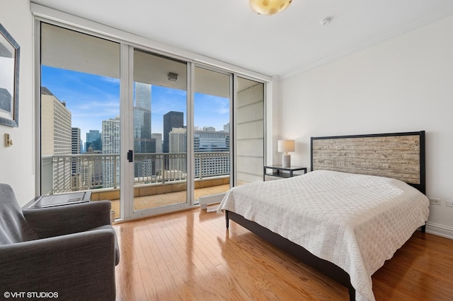bedroom featuring expansive windows, access to exterior, multiple windows, and wood finished floors