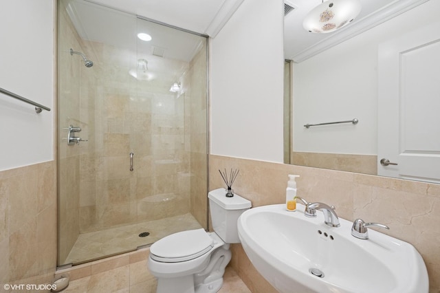 bathroom with a stall shower, tile walls, toilet, and a sink