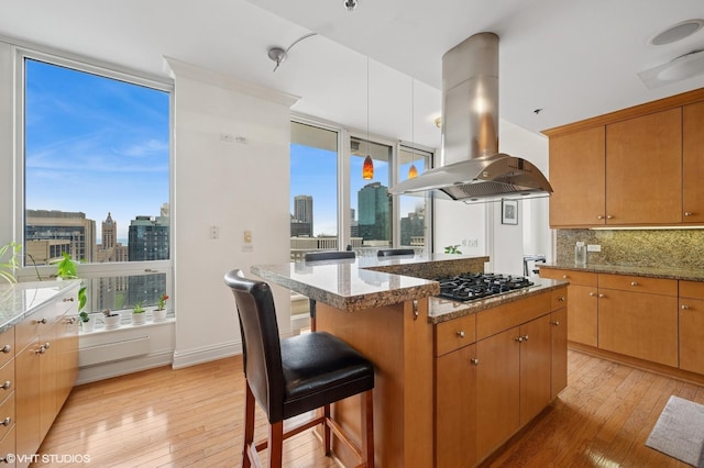 kitchen featuring gas cooktop, a city view, light wood-type flooring, and island range hood