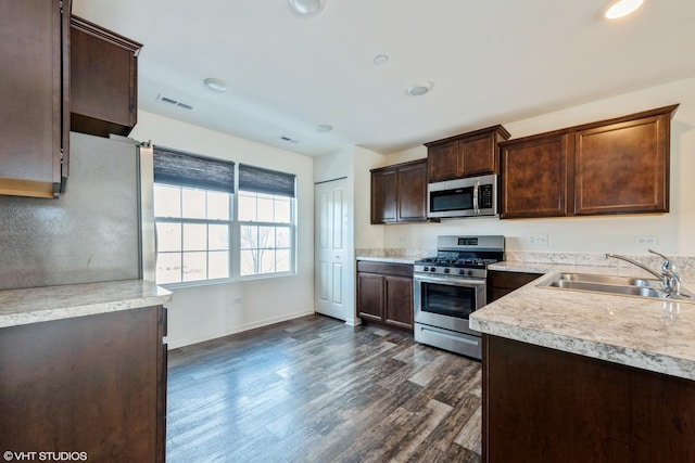 kitchen featuring a sink, stainless steel appliances, dark wood finished floors, visible vents, and light countertops