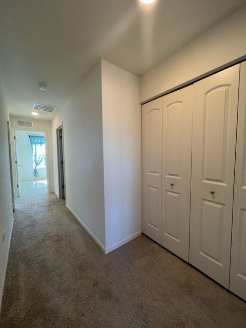 hallway featuring baseboards, carpet flooring, and visible vents