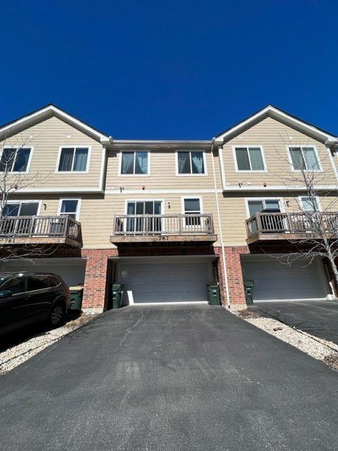 view of front of house with driveway, brick siding, and an attached garage