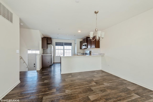 kitchen featuring dark brown cabinets, a peninsula, a chandelier, and dark wood-type flooring