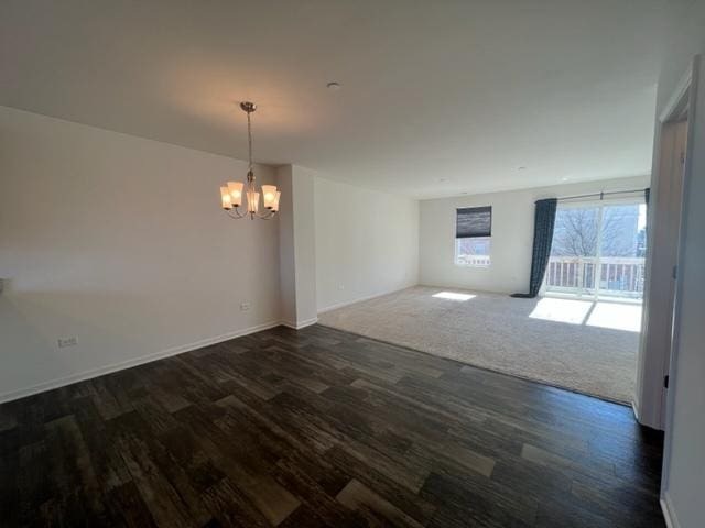 unfurnished dining area featuring dark wood-type flooring, baseboards, and a notable chandelier