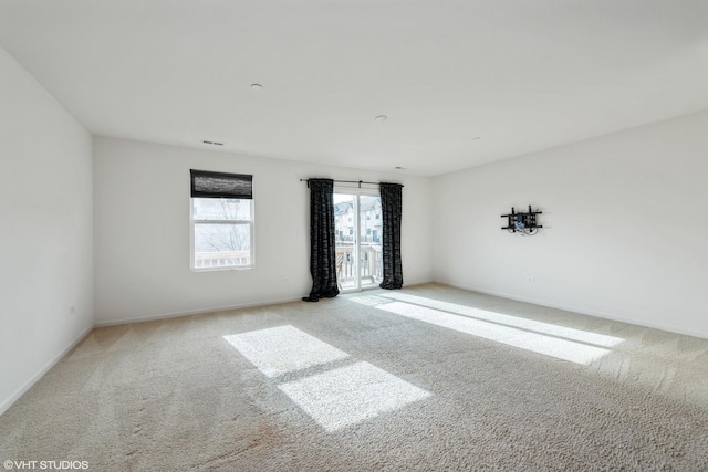 carpeted spare room featuring baseboards and visible vents