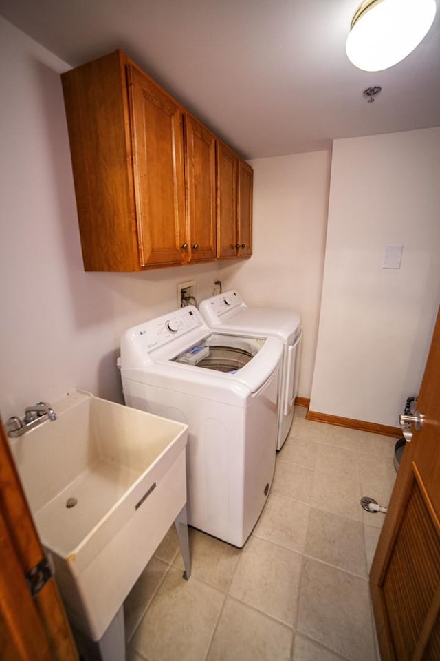 laundry room featuring washer and dryer, cabinet space, light tile patterned floors, and baseboards