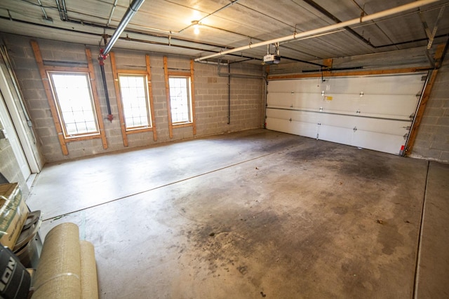garage featuring a garage door opener and concrete block wall