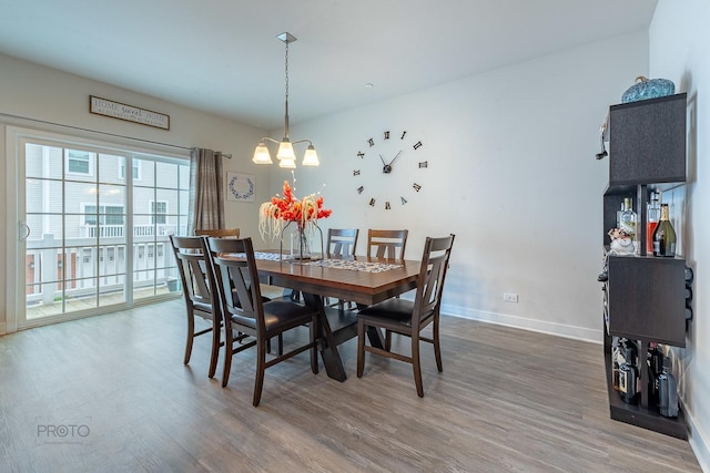 dining area featuring a chandelier, wood finished floors, and baseboards