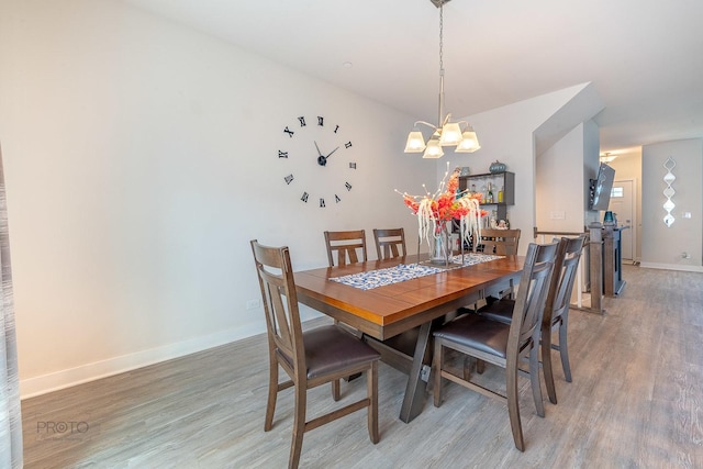 dining room with baseboards, a notable chandelier, and light wood-style flooring