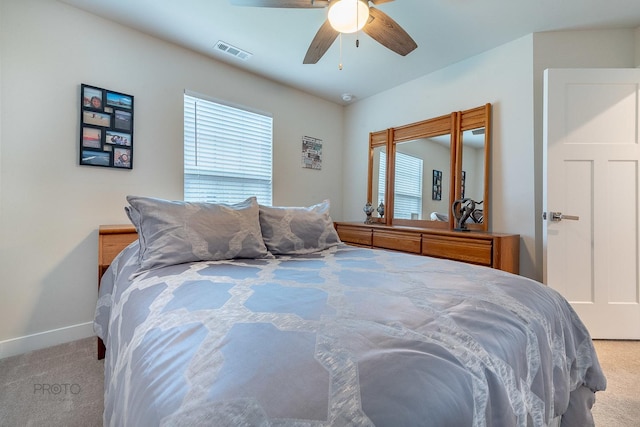 carpeted bedroom with multiple windows, visible vents, baseboards, and ceiling fan