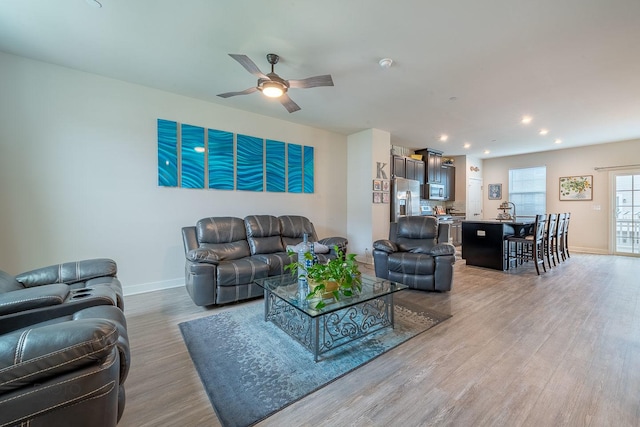 living area featuring baseboards, recessed lighting, light wood finished floors, and ceiling fan