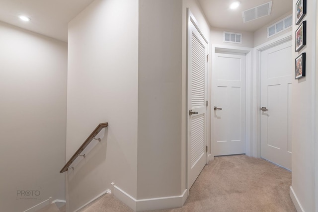 hallway with carpet, visible vents, an upstairs landing, and recessed lighting