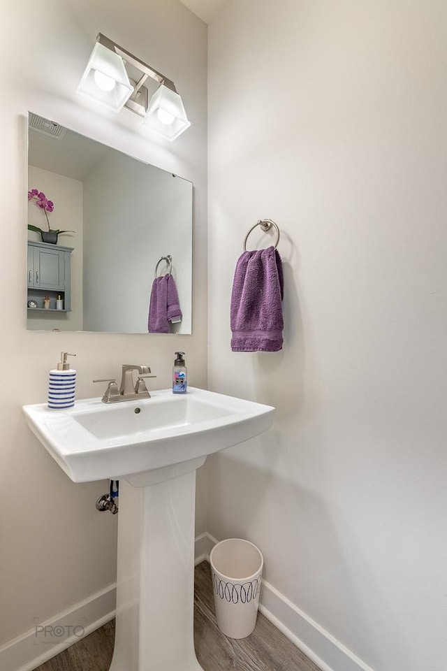 bathroom with baseboards, visible vents, and wood finished floors