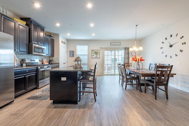 kitchen with light wood-type flooring, stainless steel appliances, baseboards, and a center island