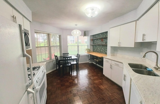 kitchen featuring white appliances, a sink, white cabinets, and a chandelier