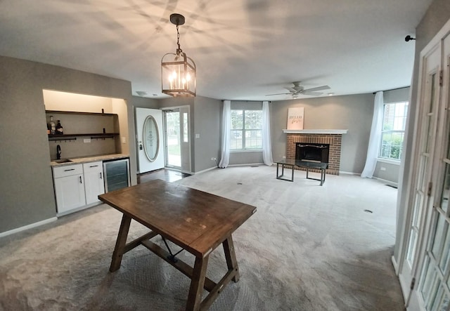 living area with wine cooler, light carpet, plenty of natural light, and a brick fireplace