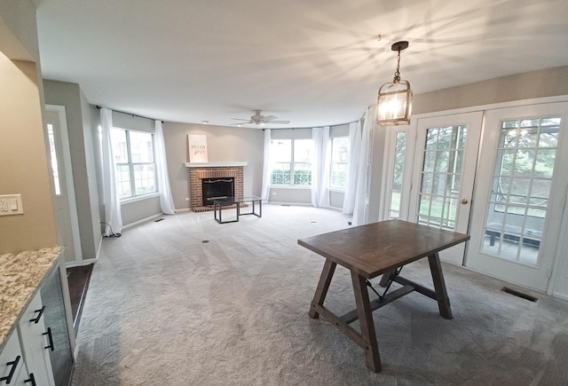 carpeted dining space featuring a brick fireplace, a ceiling fan, baseboards, and french doors