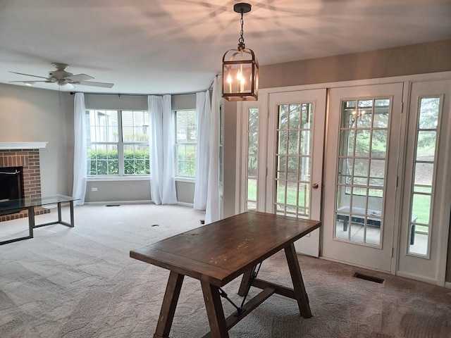 dining area with carpet flooring, ceiling fan, and a fireplace