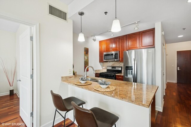 kitchen with stainless steel appliances, a sink, a peninsula, and dark wood-type flooring