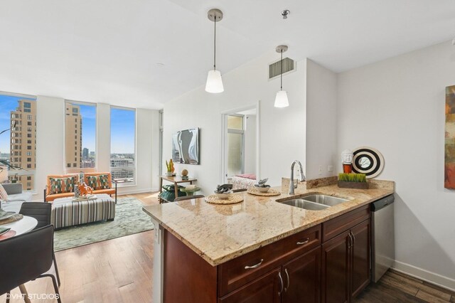 kitchen with a sink, wood finished floors, baseboards, light stone counters, and open floor plan