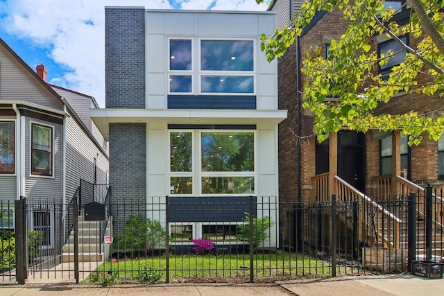 view of front of home featuring brick siding, a fenced front yard, a gate, and stucco siding