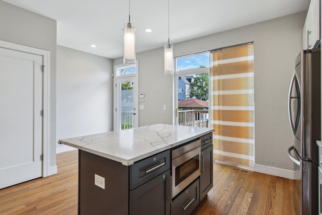 kitchen featuring stainless steel appliances, baseboards, light wood-style floors, hanging light fixtures, and light stone countertops