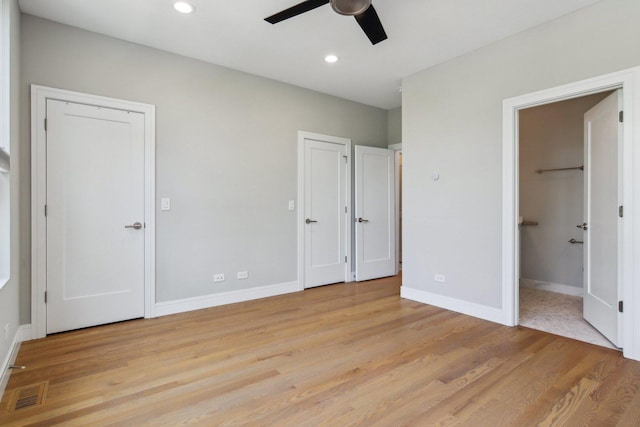 unfurnished bedroom featuring light wood-style flooring, baseboards, recessed lighting, multiple closets, and a ceiling fan