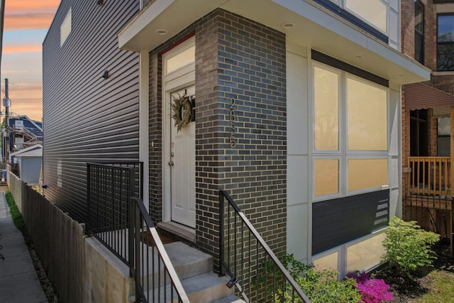 entrance to property with brick siding and fence