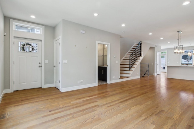entrance foyer featuring stairs, recessed lighting, light wood-style flooring, a chandelier, and baseboards