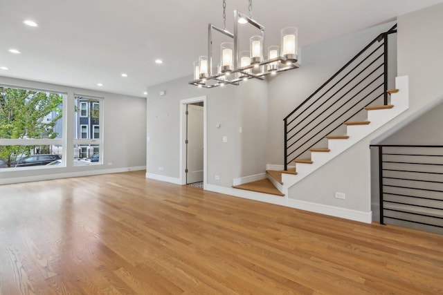 unfurnished living room with recessed lighting, light wood-style floors, baseboards, and stairs