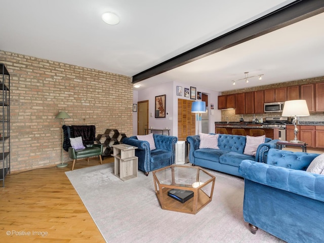 living area featuring brick wall and light wood-style flooring