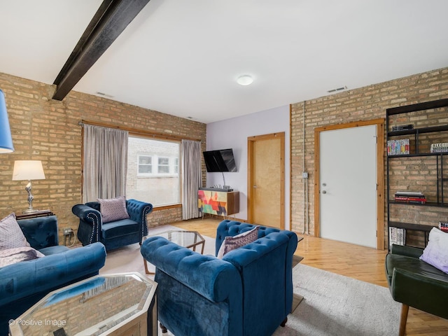 living room featuring brick wall, beam ceiling, visible vents, and wood finished floors
